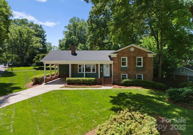 1226 Tarrington Ave, Charlotte, NC 28205 - tri-level home with concrete driveway, a chimney, a carport, a front lawn, and brick siding