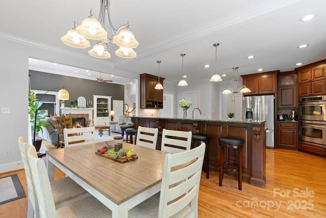 134 Brightmore Cir, Rutherfordton, NC 28139 - dining space with a chandelier, light wood finished floors, a ceiling fan, recessed lighting, and a warm lit fireplace