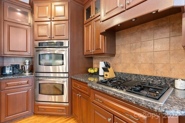 134 Brightmore Cir, Rutherfordton, NC 28139 - kitchen featuring appliances with stainless steel finishes, brown cabinets, backsplash, and glass insert cabinets