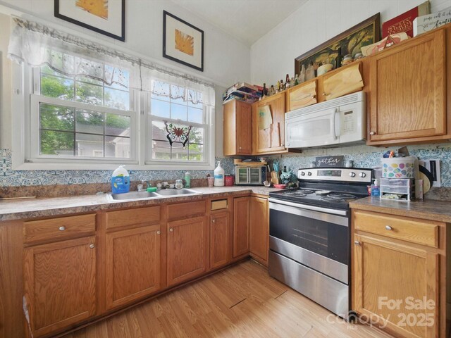 211 S Rowan Ave, Spencer, NC 28159 - kitchen featuring white microwave, electric stove, a sink, light wood-type flooring, and brown cabinetry
