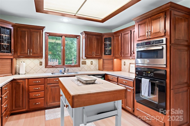 1201 Cliffspring Ct, Winston Salem, NC 27104 - kitchen with a sink, light countertops, tasteful backsplash, glass insert cabinets, and light wood-style flooring