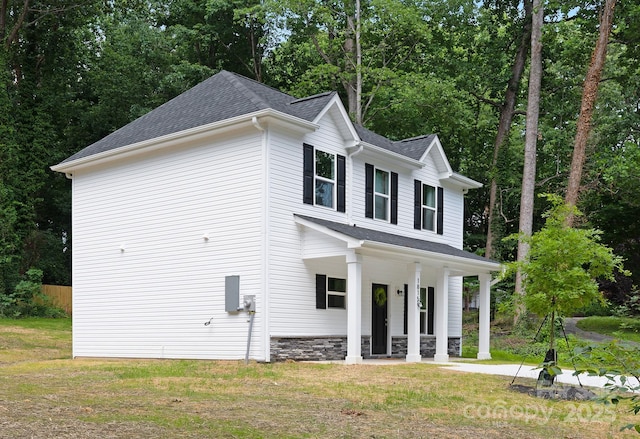 1815 Wildwood Dr, Charlotte, NC 28214 - view of property exterior featuring covered porch, roof with shingles, view of scattered trees, stone siding, and a yard
