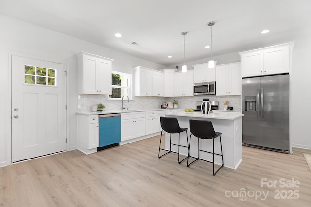 1815 Wildwood Dr, Charlotte, NC 28214 - kitchen featuring appliances with stainless steel finishes, light countertops, light wood-type flooring, backsplash, and recessed lighting