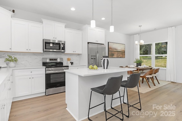 1815 Wildwood Dr, Charlotte, NC 28214 - kitchen featuring stainless steel appliances, decorative backsplash, a breakfast bar area, light wood-style floors, and recessed lighting