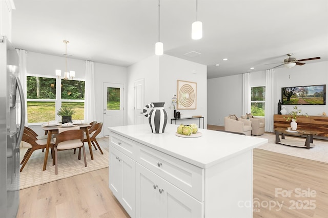 1815 Wildwood Dr, Charlotte, NC 28214 - kitchen with freestanding refrigerator, a kitchen island, light wood-style flooring, white cabinets, and decorative light fixtures