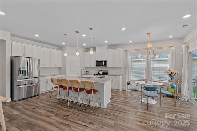 1344 Sweet Pea St, Monroe, NC 28110 - kitchen with appliances with stainless steel finishes, a sink, light wood finished floors, white cabinets, and a kitchen island with sink