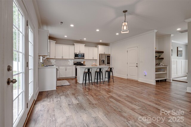 360 Sundown Rd, Mooresville, NC 28117 - kitchen with stainless steel appliances, crown molding, backsplash, a kitchen island, and white cabinetry