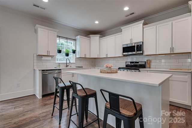 360 Sundown Rd, Mooresville, NC 28117 - kitchen with appliances with stainless steel finishes, a kitchen breakfast bar, a kitchen island, white cabinetry, and light countertops