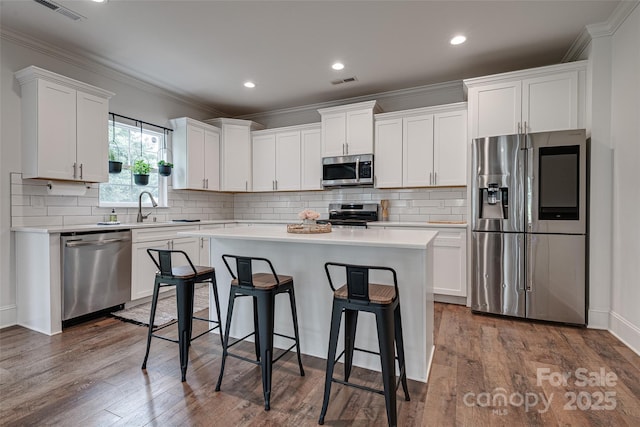 360 Sundown Rd, Mooresville, NC 28117 - kitchen featuring appliances with stainless steel finishes, ornamental molding, a kitchen island, a breakfast bar area, and white cabinetry