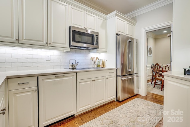 525 Queens Rd, Charlotte, NC 28207 - kitchen with appliances with stainless steel finishes, crown molding, light wood-style flooring, decorative backsplash, and light countertops