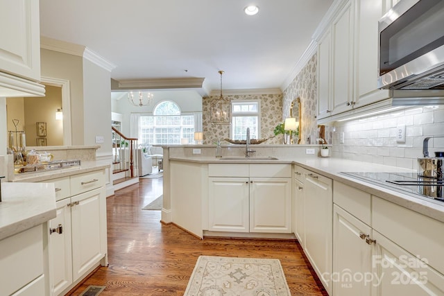 525 Queens Rd, Charlotte, NC 28207 - kitchen featuring stainless steel microwave, a sink, ornamental molding, a peninsula, and a chandelier