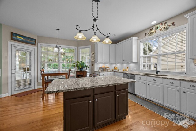 10703 Back Ridge Rd, Charlotte, NC 28277 - kitchen featuring stainless steel dishwasher, a sink, white cabinets, light wood-type flooring, and a center island