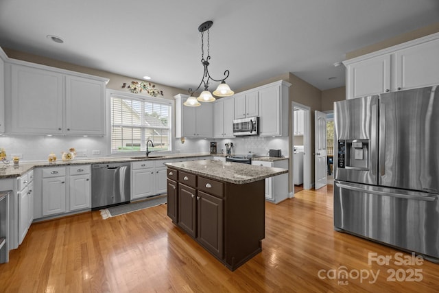 10703 Back Ridge Rd, Charlotte, NC 28277 - kitchen with stainless steel appliances, a sink, light wood-type flooring, decorative backsplash, and white cabinets