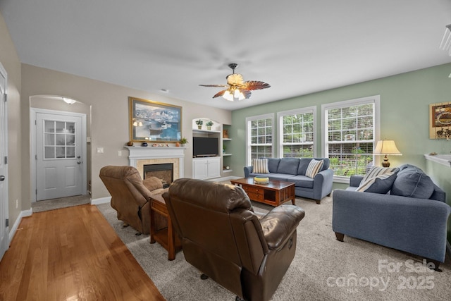 10703 Back Ridge Rd, Charlotte, NC 28277 - living area with a tiled fireplace, ceiling fan, wood finished floors, arched walkways, and built in features