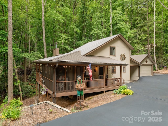 141 Creekside Dr, Maggie Valley, NC 28751 - rustic home with a chimney, a view of trees, asphalt driveway, metal roof, and a porch