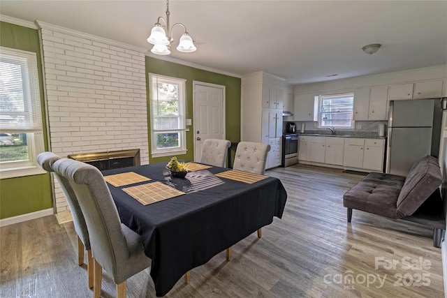901 Echo Glen Rd, Charlotte, NC 28213 - dining room with a chandelier, light wood-style floors, crown molding, baseboards, and a brick fireplace