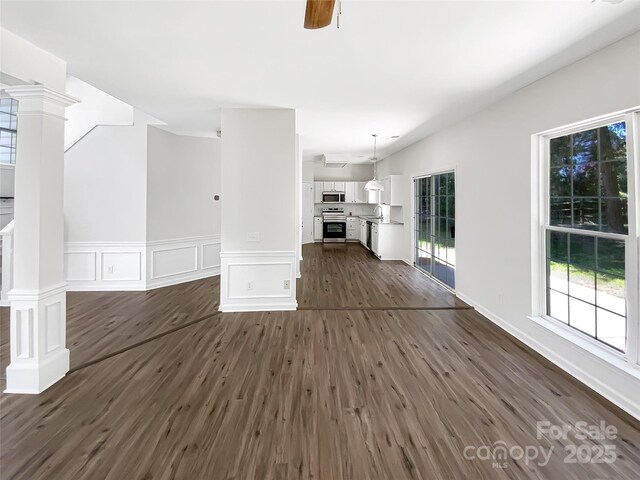 6413 Fillian Ln, Charlotte, NC 28269 - unfurnished living room with decorative columns, dark wood finished floors, a wainscoted wall, a decorative wall, and ceiling fan