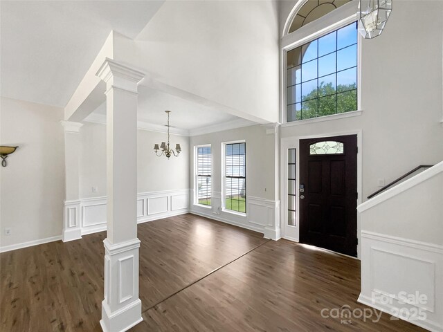 6413 Fillian Ln, Charlotte, NC 28269 - foyer entrance with decorative columns, a chandelier, a decorative wall, wood finished floors, and a towering ceiling