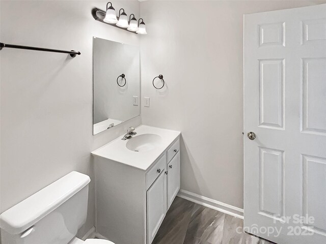6413 Fillian Ln, Charlotte, NC 28269 - bathroom featuring vanity, toilet, wood finished floors, and baseboards