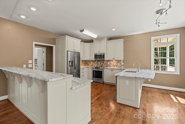 1819 Brompton Ct, Newton, NC 28658 - kitchen with stainless steel appliances, a peninsula, a breakfast bar area, backsplash, and light wood-style flooring