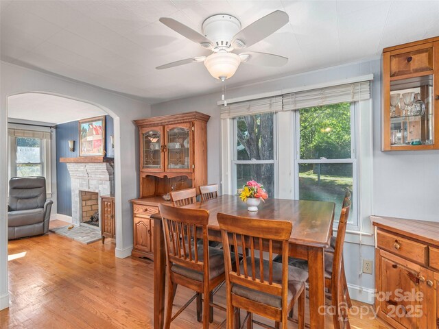 78 Hardin Ln, Clyde, NC 28721 - dining area with a fireplace with raised hearth, ceiling fan, healthy amount of natural light, and light wood-style floors