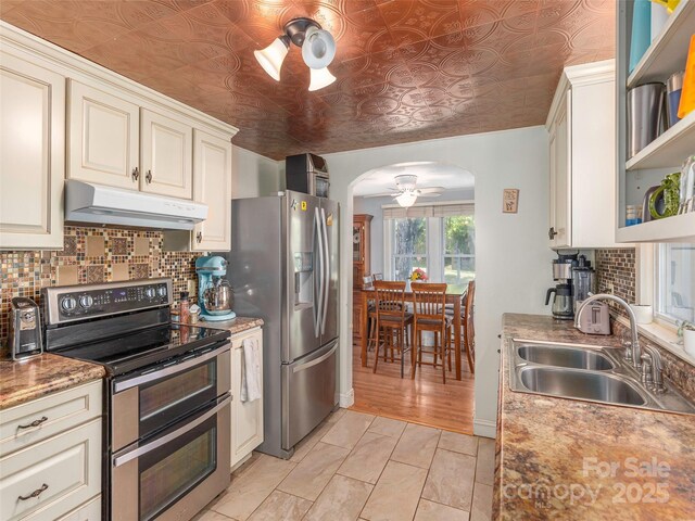 78 Hardin Ln, Clyde, NC 28721 - kitchen with under cabinet range hood, stainless steel appliances, a sink, arched walkways, and a ceiling fan