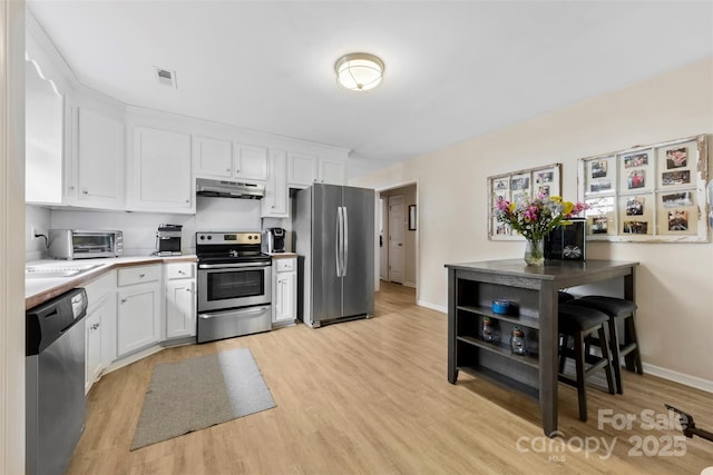 122 Pratt St, Belmont, NC 28012 - kitchen with stainless steel appliances, under cabinet range hood, light wood finished floors, and white cabinets