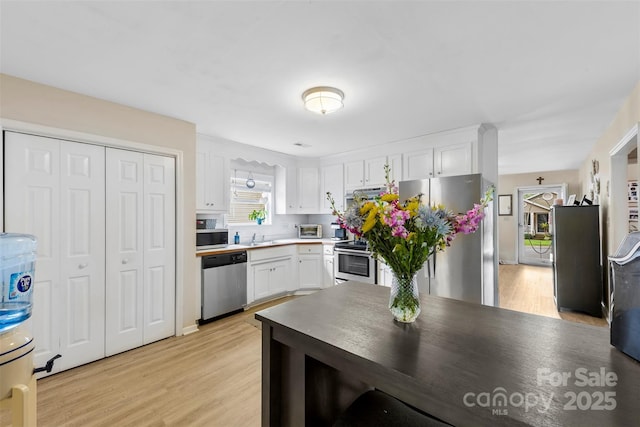 122 Pratt St, Belmont, NC 28012 - kitchen with appliances with stainless steel finishes, white cabinets, light wood-style flooring, tasteful backsplash, and a sink