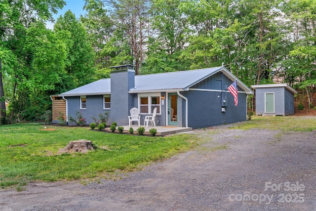 28 Reynolds School Rd, Asheville, NC 28803 - view of front facade featuring a chimney, a front lawn, metal roof, brick siding, and view of scattered trees