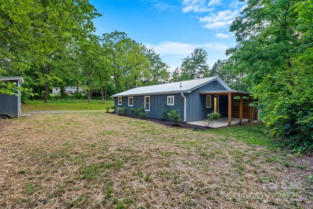 28 Reynolds School Rd, Asheville, NC 28803 - back of house featuring board and batten siding, a yard, a patio, and metal roof