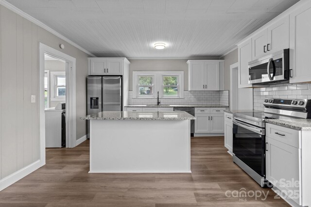 1406 Upper Enochville Rd, Kannapolis, NC 28081 - kitchen featuring appliances with stainless steel finishes, washer / clothes dryer, a sink, ornamental molding, and tasteful backsplash