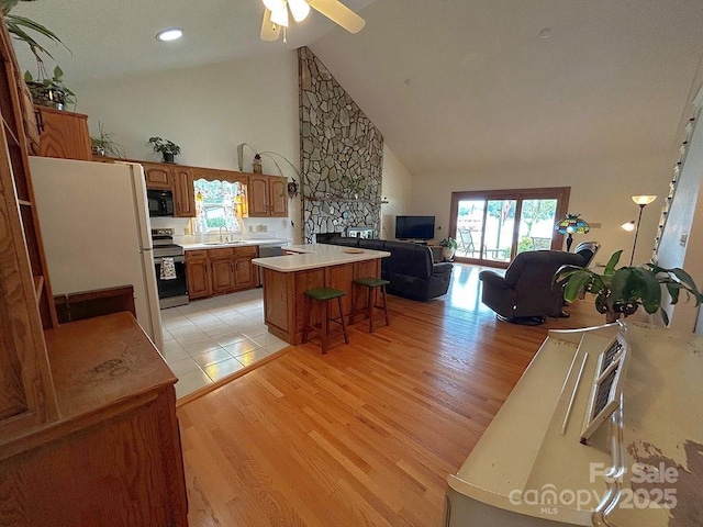 4574 Ivy Run Ln, Denver, NC 28037 - kitchen featuring appliances with stainless steel finishes, brown cabinets, open floor plan, plenty of natural light, and high vaulted ceiling