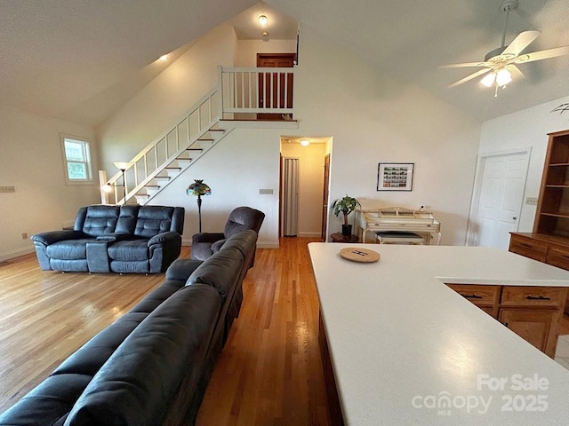 4574 Ivy Run Ln, Denver, NC 28037 - living room featuring ceiling fan, light wood-style floors, high vaulted ceiling, stairway, and baseboards