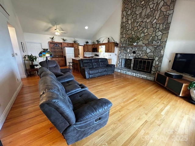 4574 Ivy Run Ln, Denver, NC 28037 - living room featuring ceiling fan, light wood-type flooring, a stone fireplace, vaulted ceiling, and baseboards