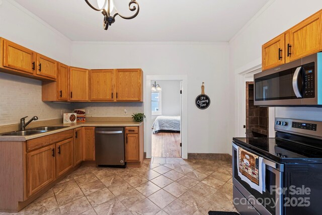 61 First St, Marion, NC 28752 - kitchen with appliances with stainless steel finishes, a sink, ornamental molding, brown cabinets, and light countertops