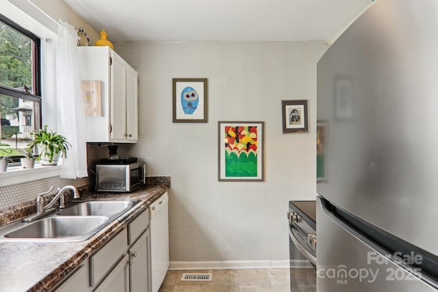 615 Biltmore Ave Unit K2, Asheville, NC 28803 - kitchen with stainless steel appliances, a sink, white cabinetry, dark countertops, and decorative backsplash