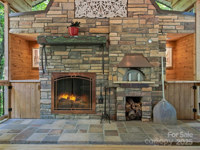 105 Blackberry Ln, Fairview, NC 28730 - unfurnished living room featuring a fireplace, stone tile flooring, and wood walls