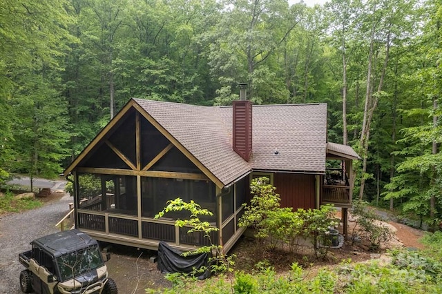 45 Boulder Creek Ln Unit 28, Tuckasegee, NC 28783 - view of front facade with a wooded view, a chimney, a sunroom, and a shingled roof