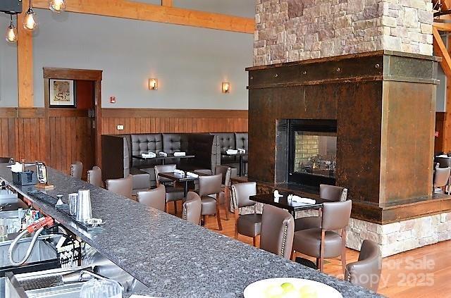 45 Boulder Creek Ln Unit 28, Tuckasegee, NC 28783 - kitchen with wainscoting, a multi sided fireplace, wood finished floors, and wood walls