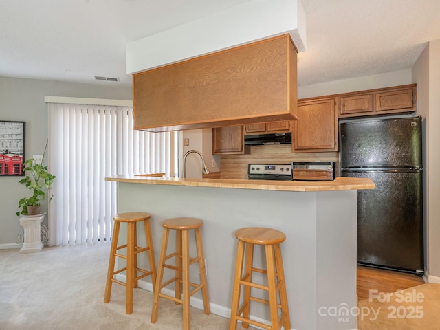 8208 Cedar Glen Dr, Charlotte, NC 28212 - kitchen with freestanding refrigerator, stainless steel range oven, under cabinet range hood, a kitchen breakfast bar, and backsplash