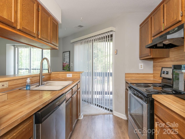 8208 Cedar Glen Dr, Charlotte, NC 28212 - kitchen featuring butcher block counters, appliances with stainless steel finishes, under cabinet range hood, a sink, and light wood-style floors