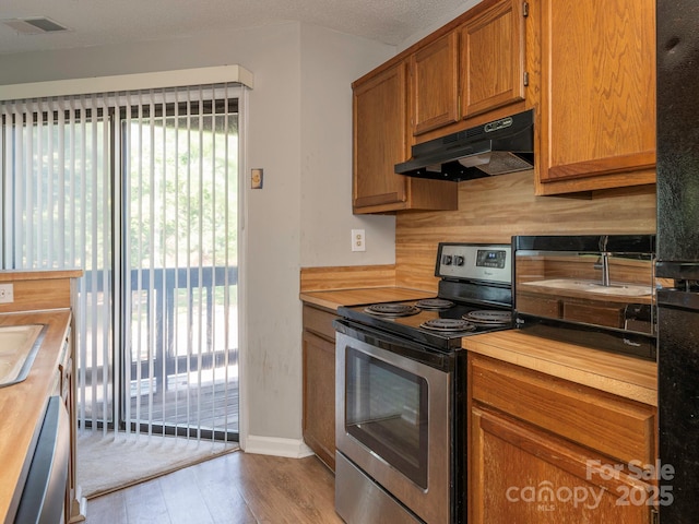 8208 Cedar Glen Dr, Charlotte, NC 28212 - kitchen with stainless steel appliances, under cabinet range hood, butcher block countertops, light wood finished floors, and a sink