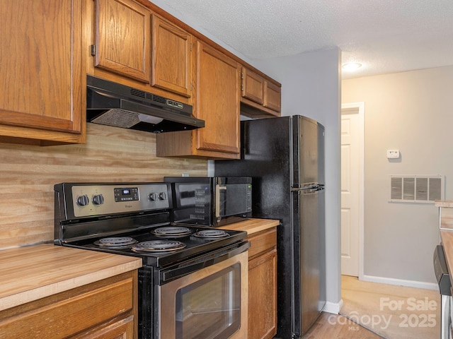 8208 Cedar Glen Dr, Charlotte, NC 28212 - kitchen with black appliances, under cabinet range hood, brown cabinetry, wood counters, and baseboards