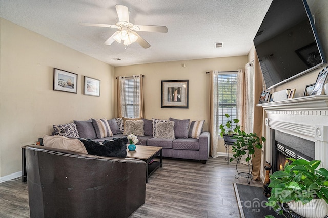 203 Alyssum Ct, Myrtle Beach, SC 29579 - living room featuring dark wood finished floors, a warm lit fireplace, a ceiling fan, baseboards, and a textured ceiling