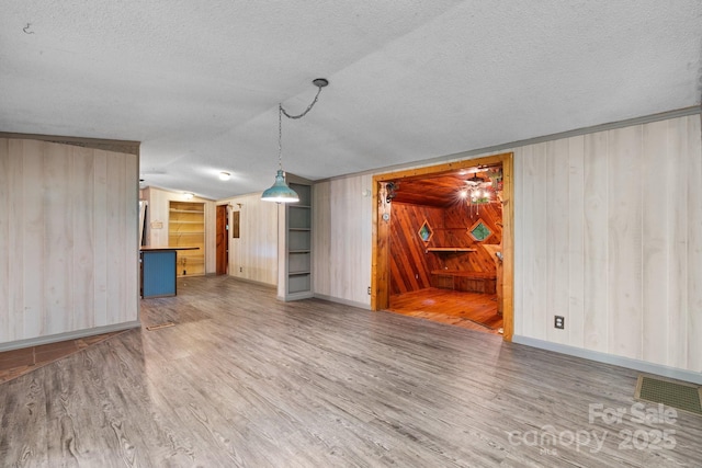 2951 Evergreen Trl, Vale, NC 28168 - unfurnished living room with wood finished floors, a textured ceiling, wood walls, baseboards, and vaulted ceiling