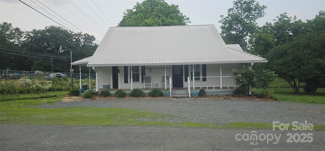 804 N Main St, Oakboro, NC 28129 - farmhouse featuring covered porch, metal roof, and gravel driveway