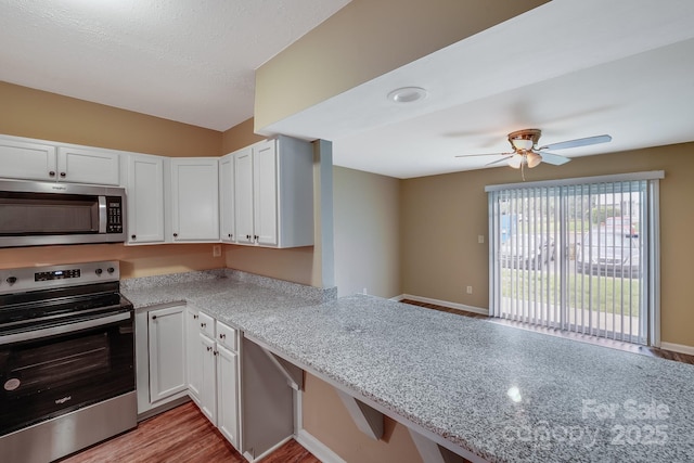809 High Meadow Ln Unit F, Charlotte, NC 28217 - kitchen with stainless steel appliances, white cabinets, a ceiling fan, light wood-style flooring, and light stone counters