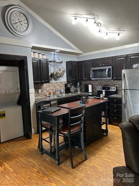 114 Wayne Ave, Kannapolis, NC 28081 - kitchen with stacked washing machine and dryer, appliances with stainless steel finishes, a textured ceiling, backsplash, and vaulted ceiling