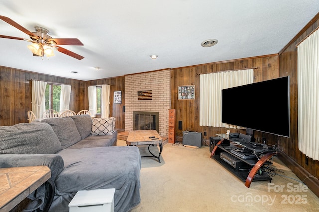 1410 Patterson St, China Grove, NC 28023 - carpeted living room featuring wooden walls, a ceiling fan, crown molding, and a fireplace