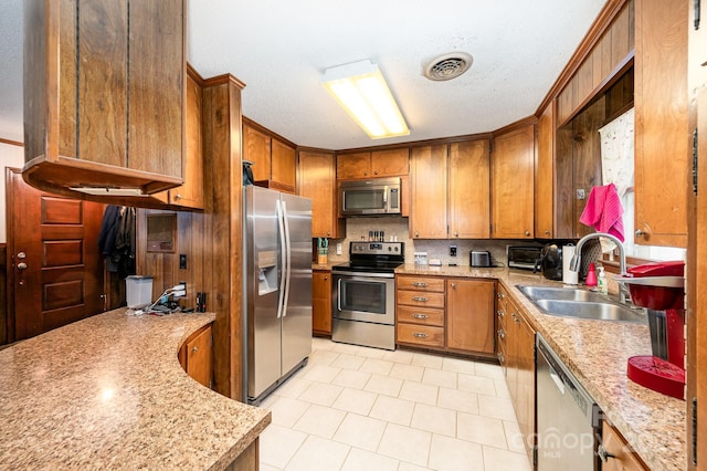 1410 Patterson St, China Grove, NC 28023 - kitchen featuring appliances with stainless steel finishes, brown cabinets, tasteful backsplash, light tile patterned floors, and a textured ceiling